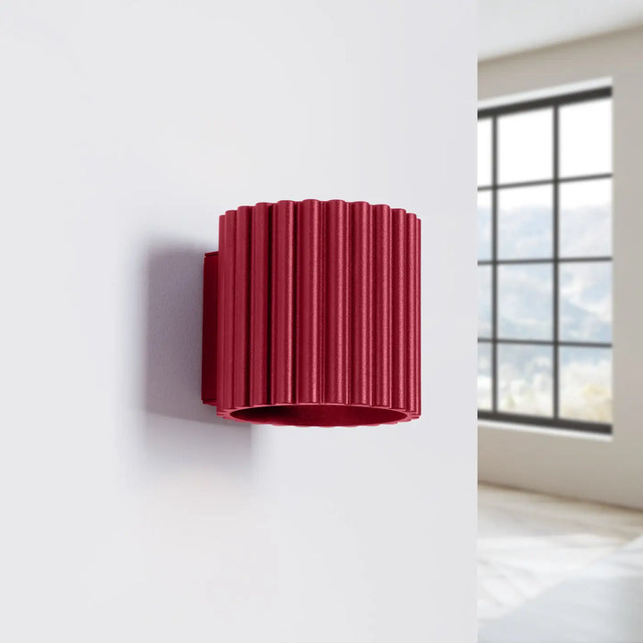 Applique murale aura bordeaux en métal rouge vibrante avec forme unique inspirée et design cylindrique moderne ribbé