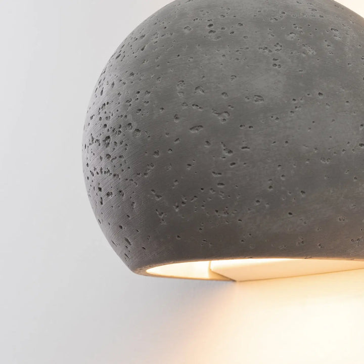 Applique murale globe en béton gris mat specklé avec une lueur chaude style industriel et charme brut