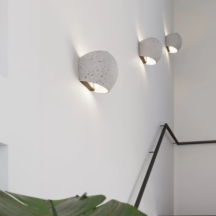 Trois appliques globe minimalistes en béton avec charme brut et style industriel à surface grise tachetée et éclairage encastré