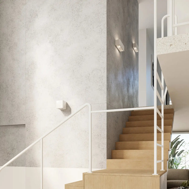 Applique murale nesta en céramique moderne avec belle lumière montée près d’un escalier minimaliste en bois clair et métal blanc