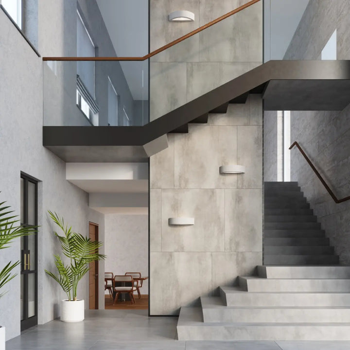 Modern concrete staircase with sleek black metal railings illuminated by l’applique murale atena creating une atmosphère harmonieuse for agencements industriels