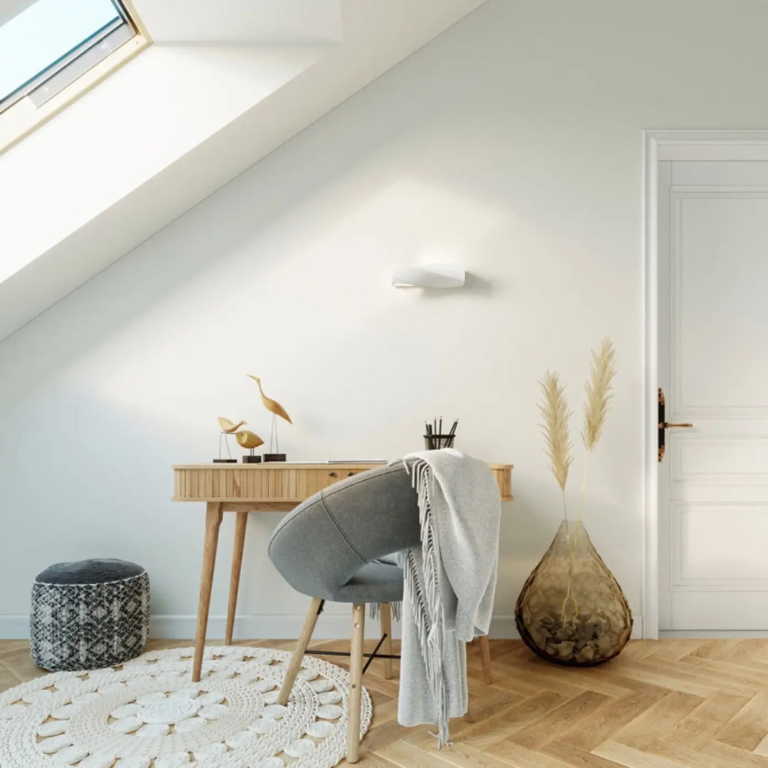 Chaise grise en tissu avec pieds en bois et jeté gris clair près dune applique murale céramique sigma mini belle lumière