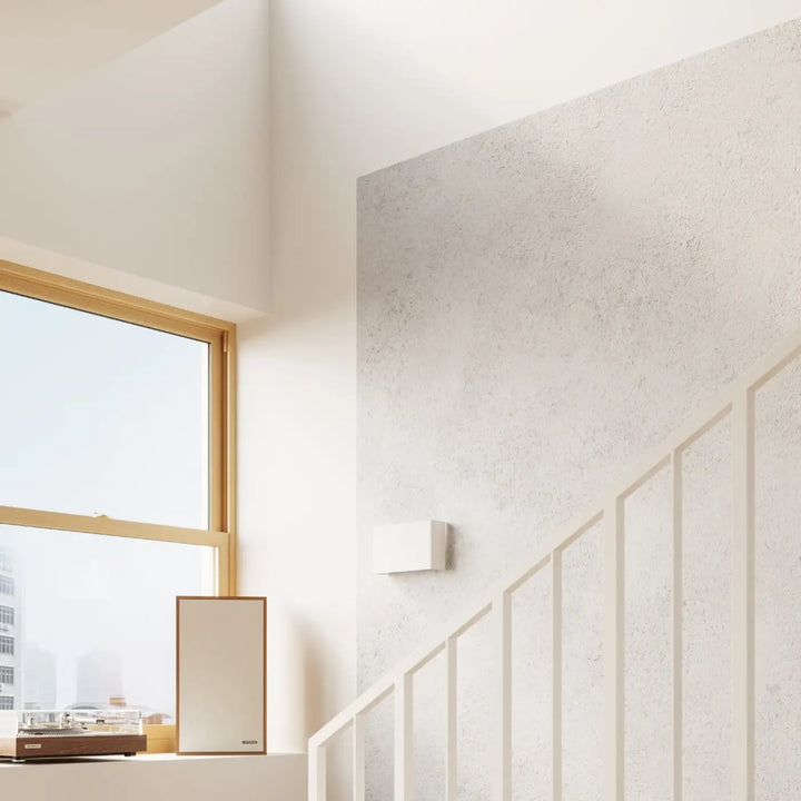 Enceinte murale beige minimaliste avec cadre en bois posée près d’une fenêtre pour une atmosphère chaleureuse murale copertura