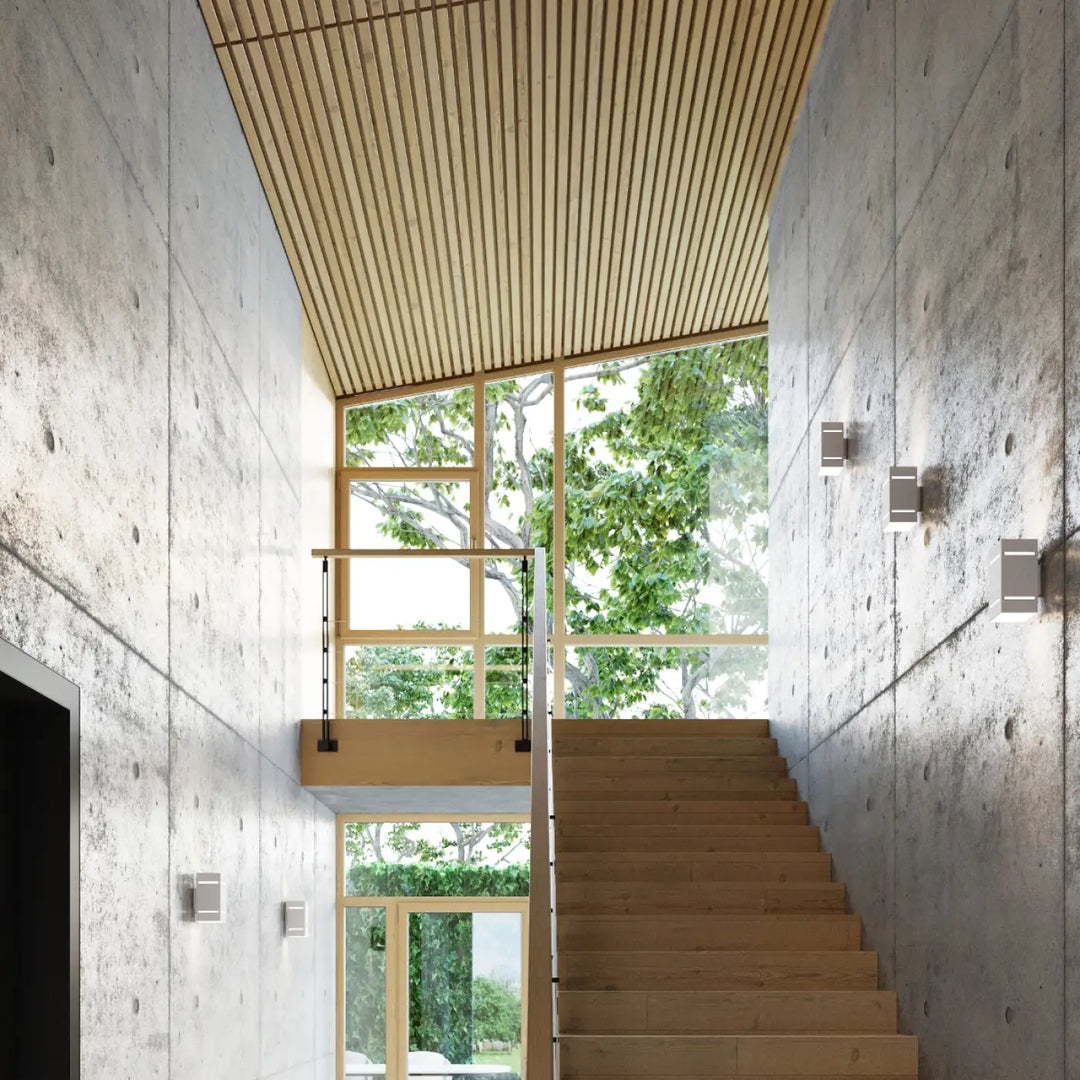 Light wood staircase with matching handrail and ceiling slats beside l’applique blocco blanc creating spectacle lumineux with perforation linéaire on concrete walls