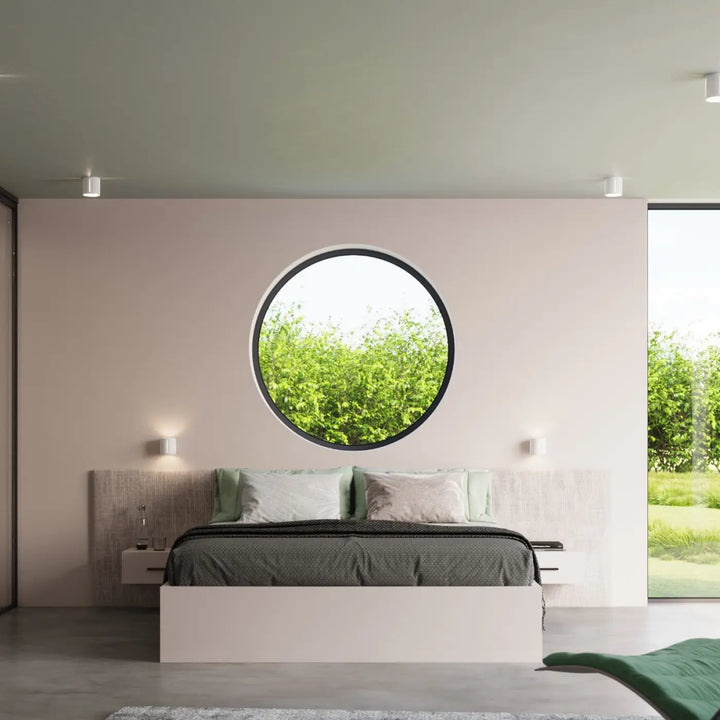 L’applique murale inez blanc avec cadre noir circulaire et perforation linéaire intégrée sur mur rose pâle