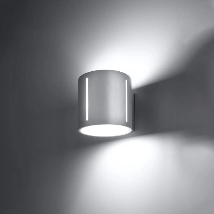 Applique murale inez blanche moderne en métal avec perforation linéaire et deux bandes led verticales émettant une lumière blanche brillante