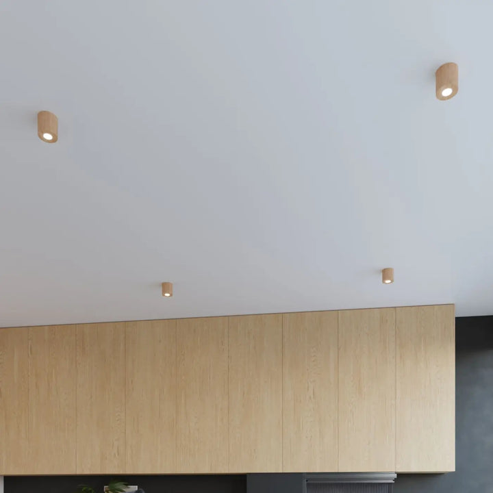 Trois spots plafond cylindriques en bois naturel montées individuellement pour une ambiance chaleureuse