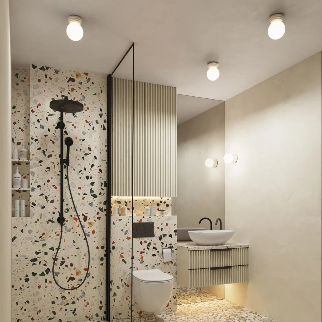 Applique murale zori beige avec douchette noire et tuyau assorti sur mur terrazzo blanc belle décoration
