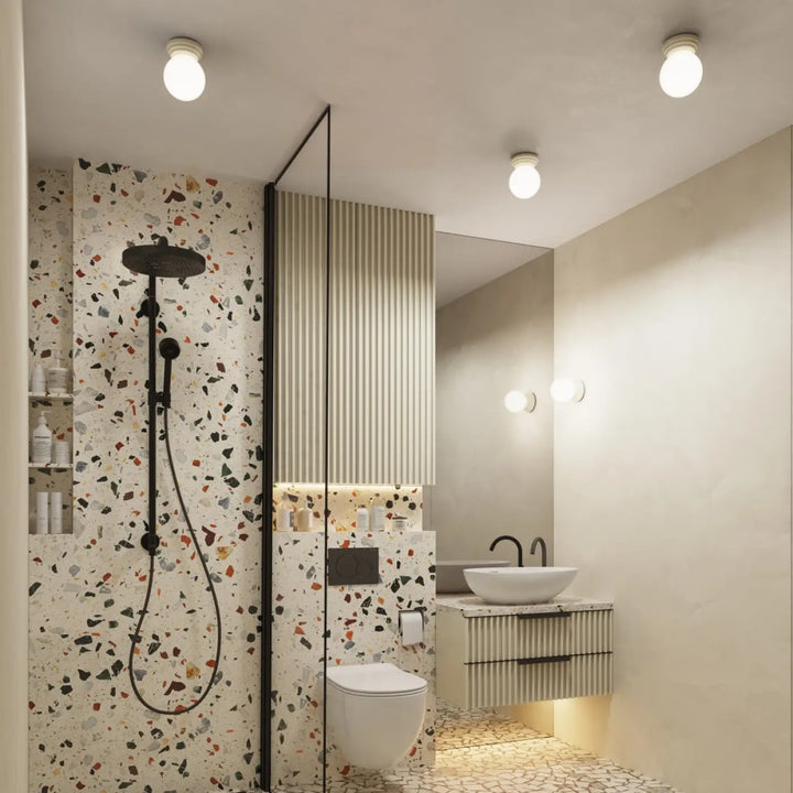 Applique murale zori beige avec douchette noire et tuyau assorti sur mur terrazzo blanc belle décoration