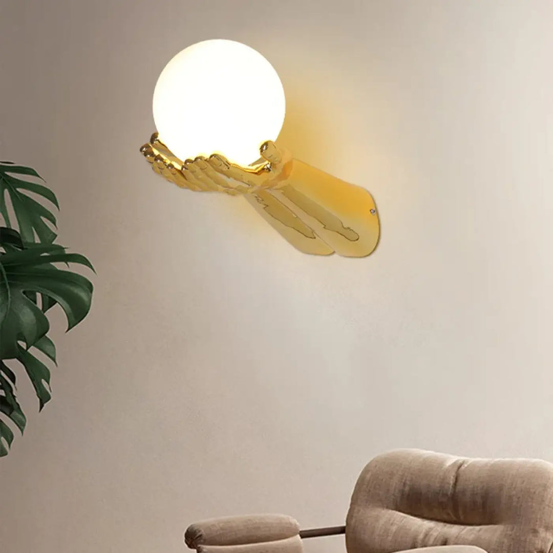 Applique murale avec brand tendu tenant une boule blanche

