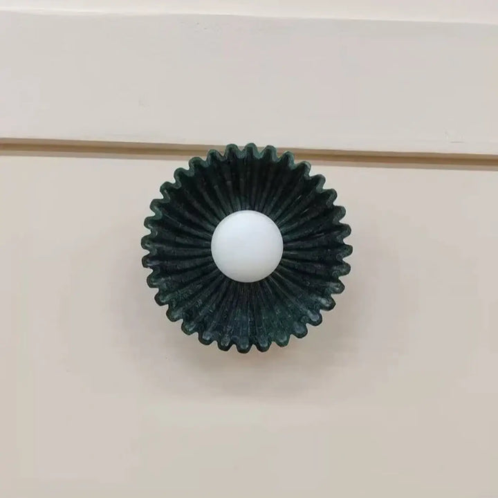 Applique murale akora avec globe lumineux central blanc et motif soleil vert foncé en forme de bouton de meuble