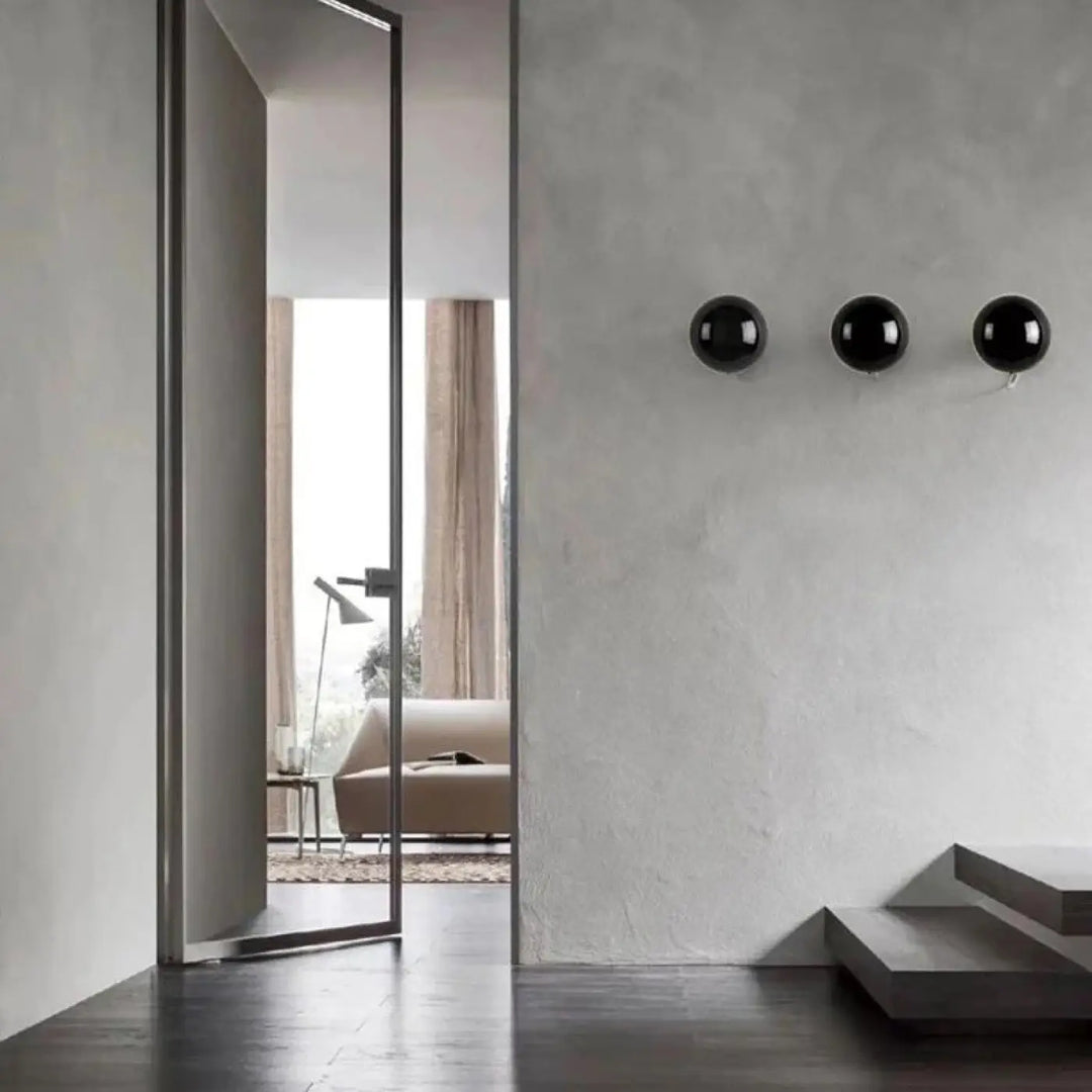 Applique murale orbys en métal miroir avec trois sphères noires brillantes offrant une lumière douce