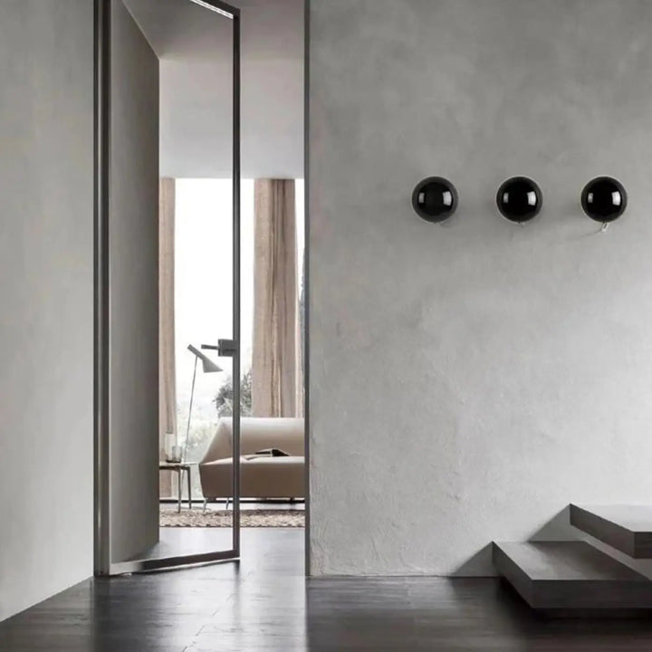 Applique murale orbys en métal miroir avec trois sphères noires brillantes offrant une lumière douce