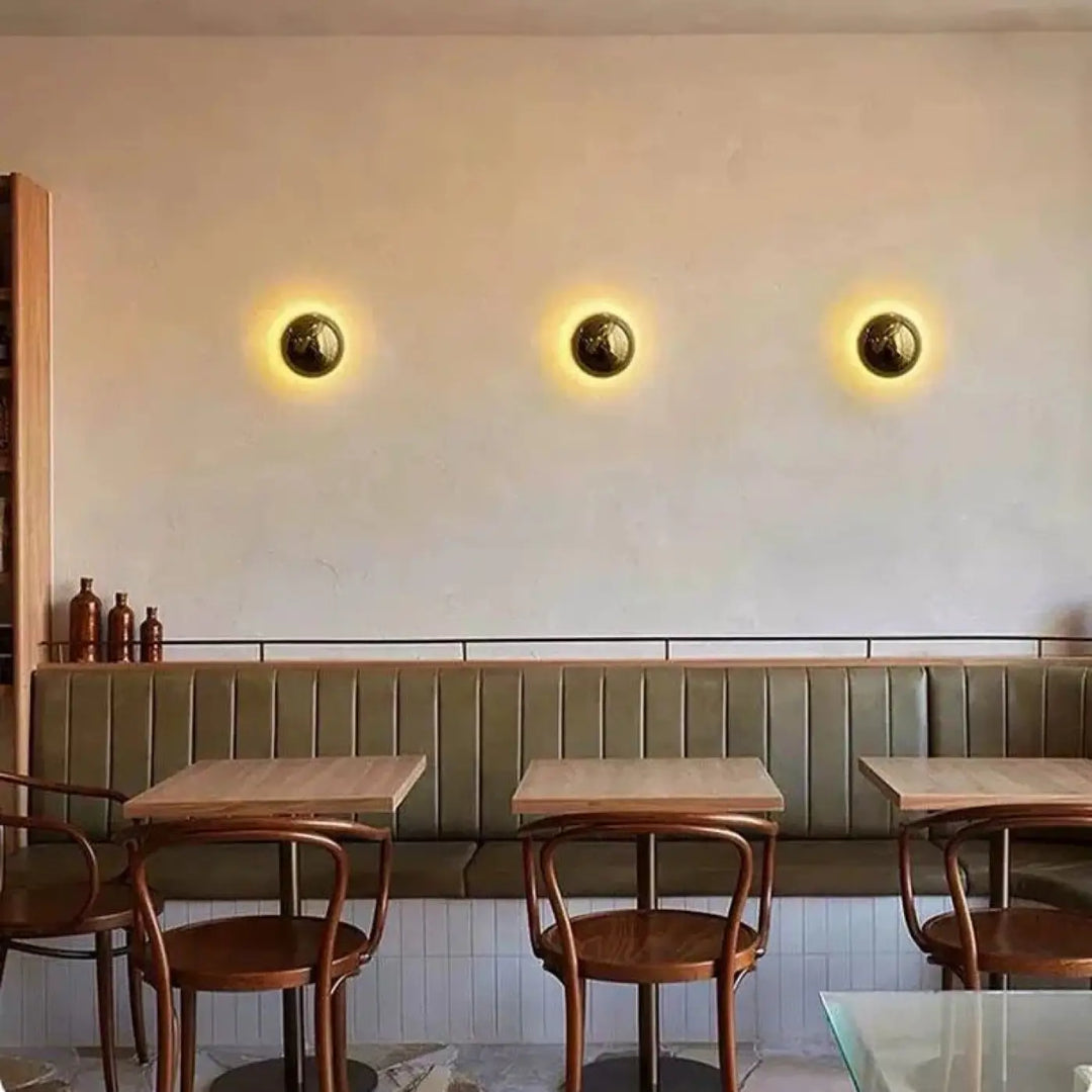 Applique murale orbys en métal miroir finition laiton avec lumière douce et surface texturée pour ambiance chaleureuse