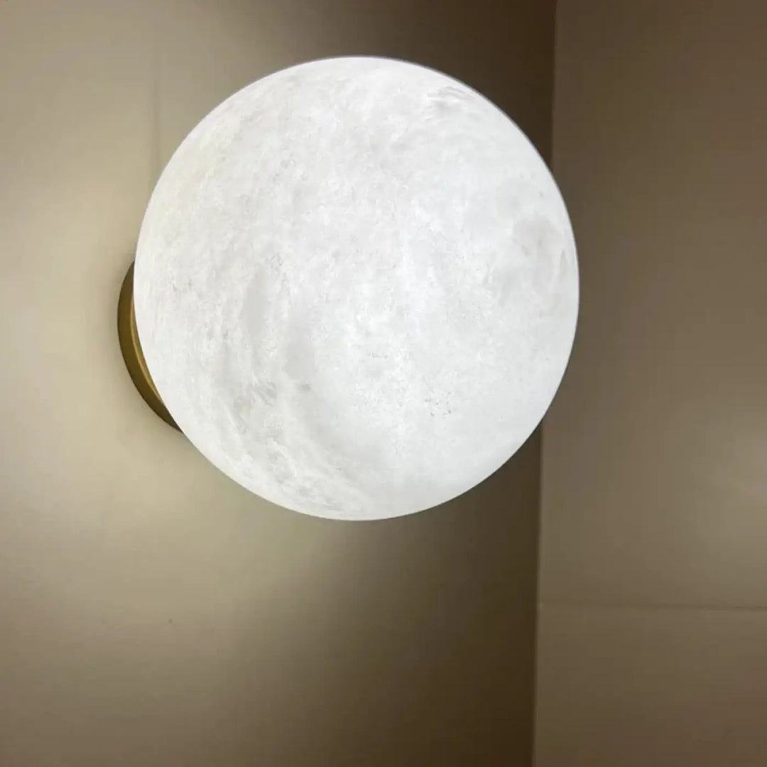 Applique murale kesto en forme de lune blanche texturée avec halo lumineux apaisant sur base dorée design