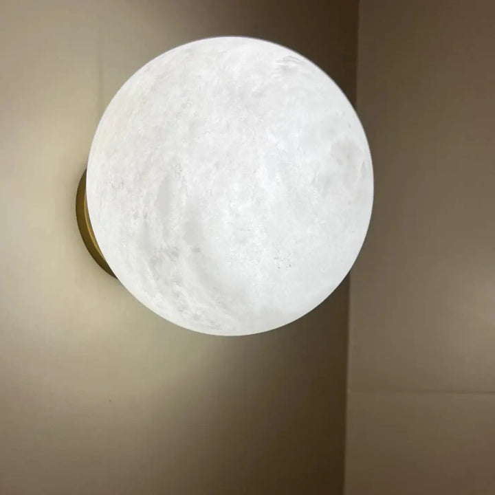 Applique murale kesto en forme de lune blanche texturée avec halo lumineux apaisant sur base dorée design