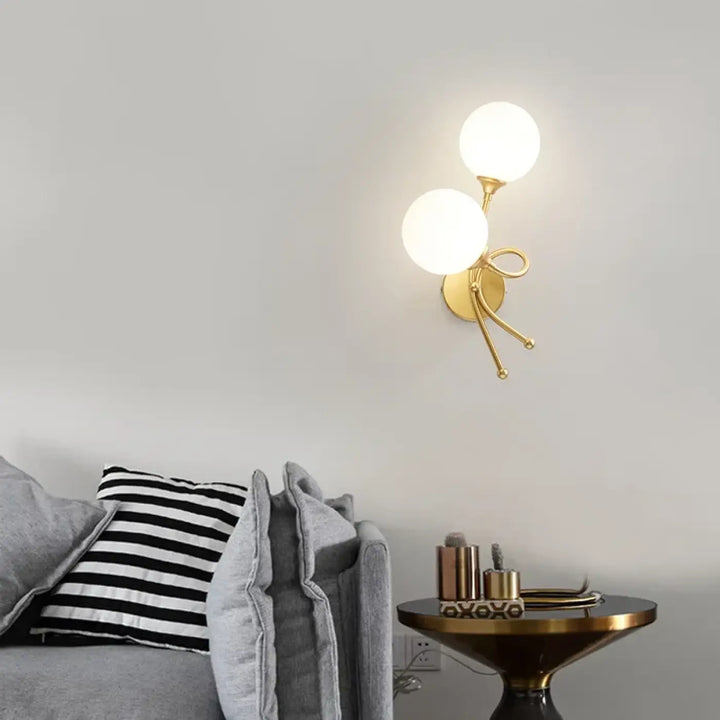 Applique murale zylo en métal doré avec deux globes en verre dépoli et bras décoratif en forme de nœud