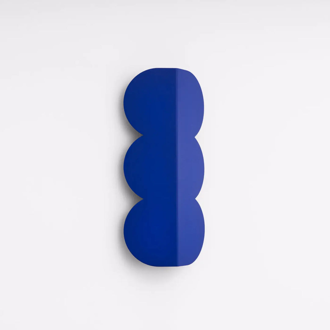 Applique murale biscuit outremer compose d’une lampe en forme ondulée caractéristique avec finition glossy bleu profond