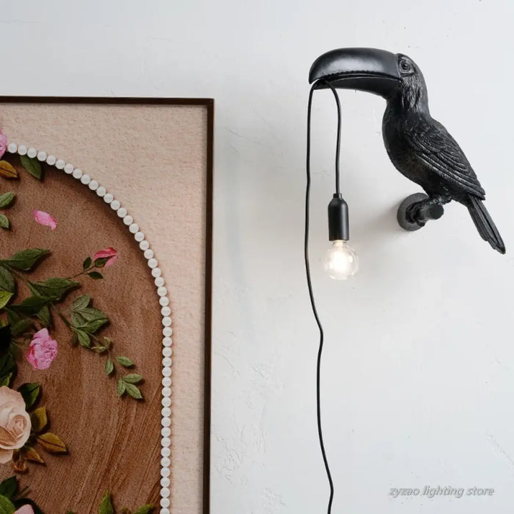 Applique murale noire design toucan perché avec finition mate texturée et ampoule exposée suspendue au bec