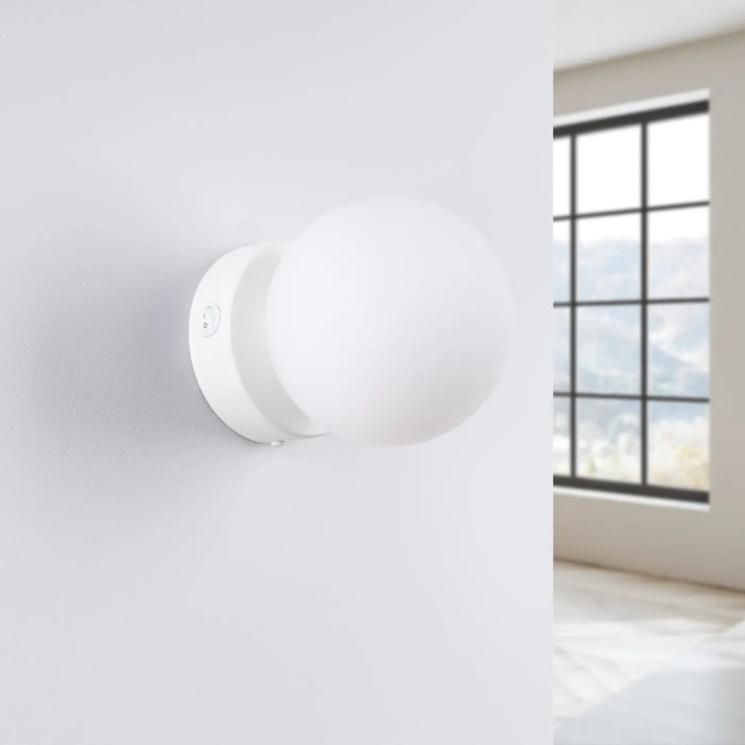 L’applique yoli avec boîtier sphérique blanc en verre dépoli et base métal d’une élégance minimaliste