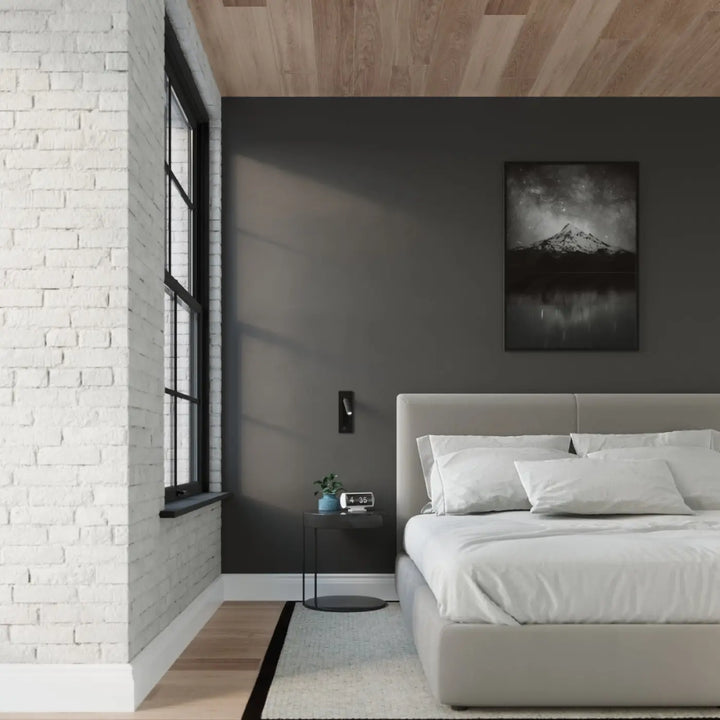 Applique murale minimaliste série enif noir installée au-dessus d un lit moderne gris avec literie blanche et coussins multiples