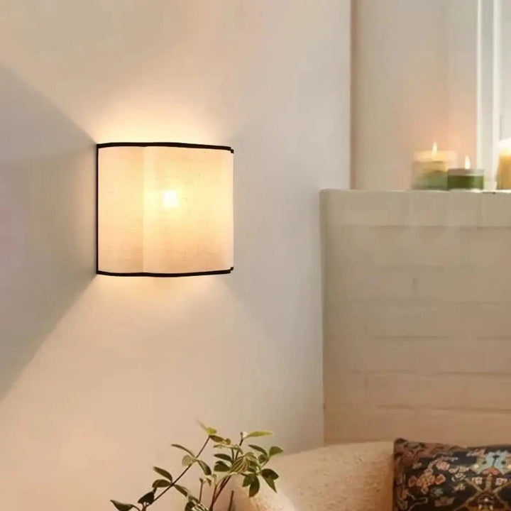 Applique murale carrée susso avec abat-jour beige en tissu et liseré noir, offrant une lumière douce pour décoration intérieure