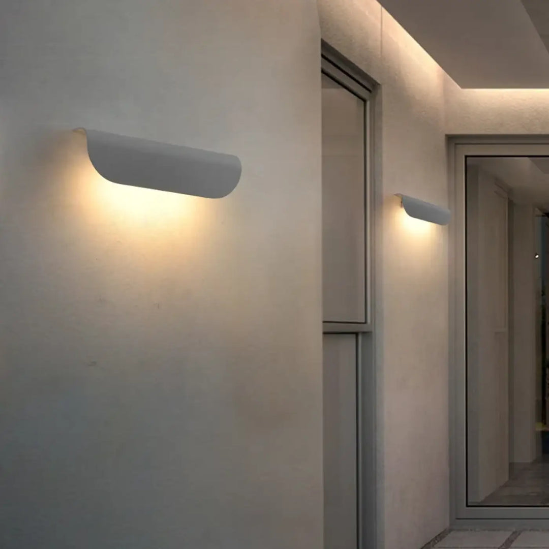Applique murale minimaliste blanche avec design incurvé diffusant une lumière ambiante chaleureuse modèle nox