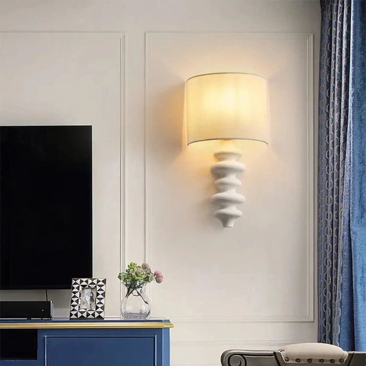 Applique murale minimaliste en céramique blanche avec base sculptée texturée et abat-jour beige en tissu doux