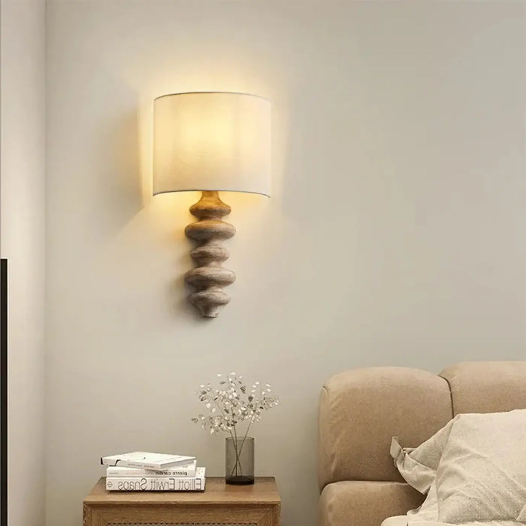 Applique murale warm-toned avec base en bois empilée texturée et abat-jour beige pour une lumière chaleureuse