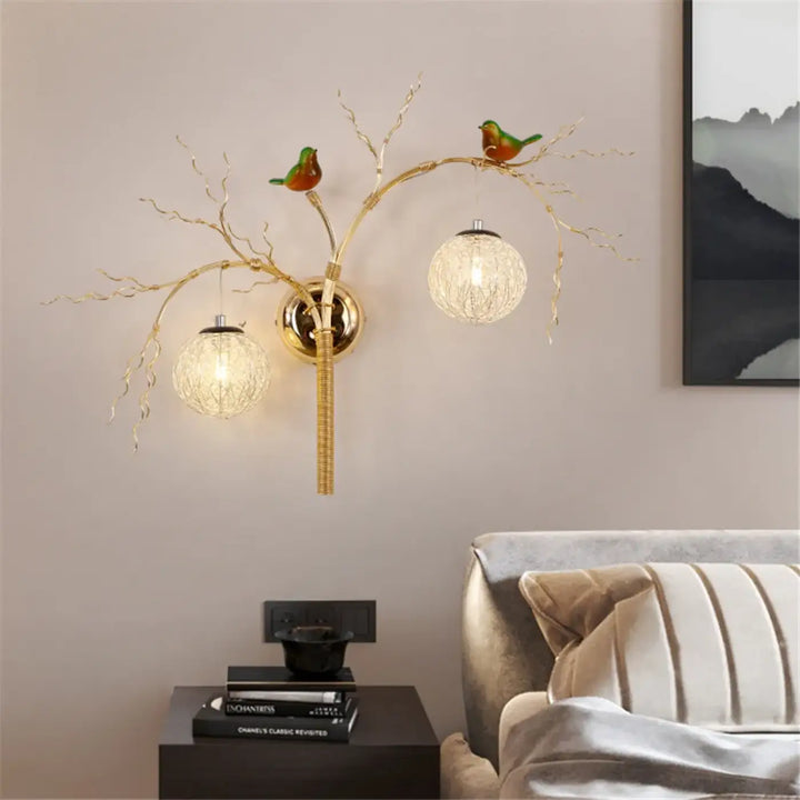 Applique murale sylvana en métal doré avec bras branchés, deux globes en verre texturé et oiseaux verts décoratifs