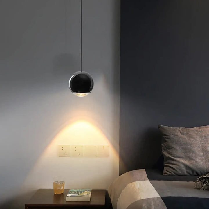 Applique murale samila sphérique noire au design moderne et minimaliste suspendue au-dessus d’une table de chevet