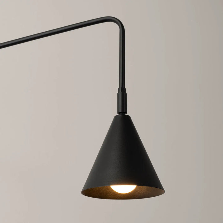 Applique murale moderne noire en finition mate avec abat-jour géométrique conique diffusant une lumière chaleureuse