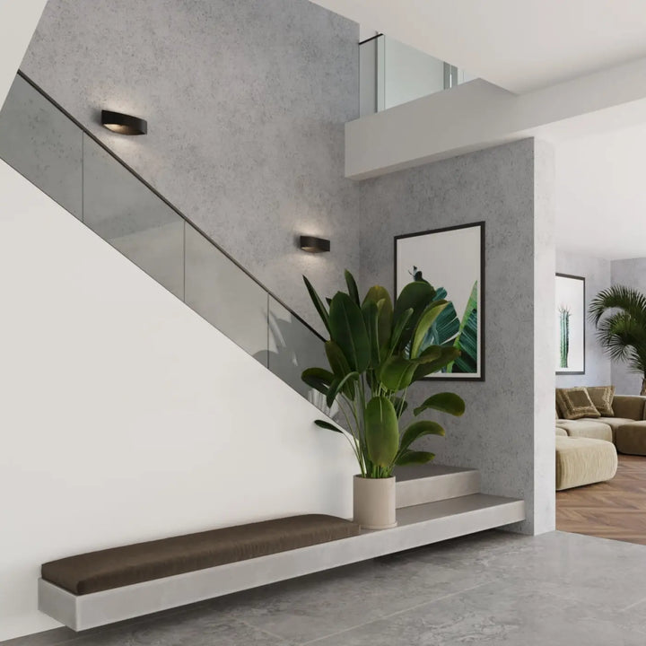 L’applique toni noir avec ornement subtil accompagner un grand plante verte dans un pot céramique beige moderne