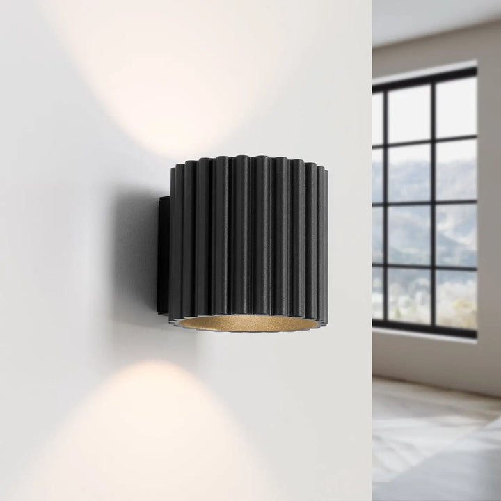 Applique murale aura noir en forme unique inspirée avec cylindre noir et intérieur doré chaud à rainures verticales