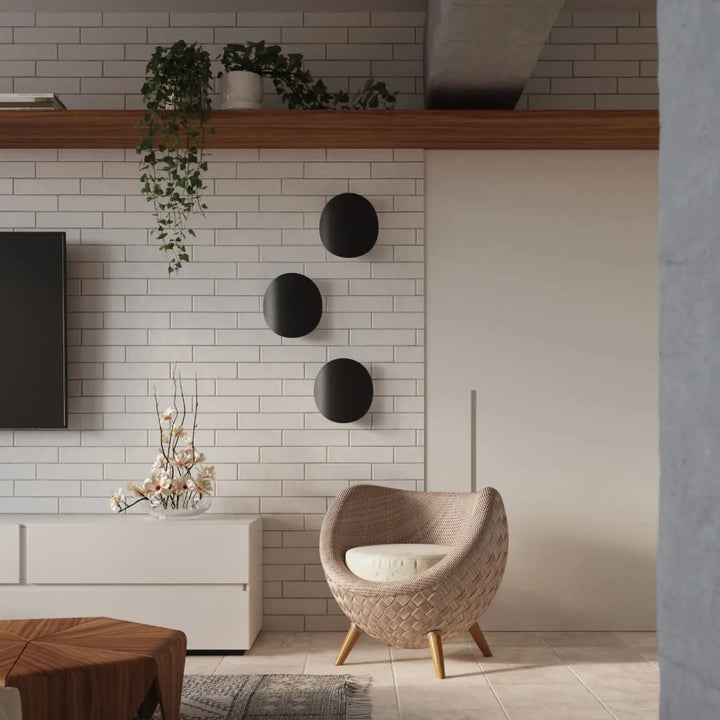 Applique murale senses noire présentée avec un fauteuil beige tissé en bois et coussin blanc dans un design original fera luminaire intemporel