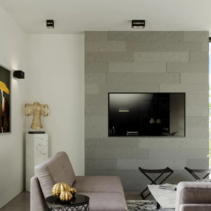 Applique murale moderne lobo maxi noir avec perforation lobo montée sur un mur en pierre grise