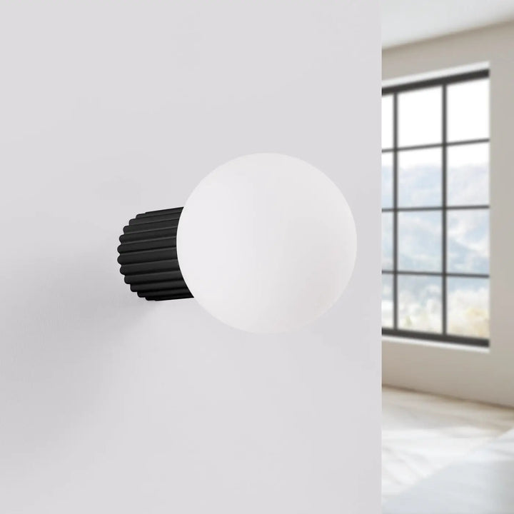 Applique murale lampe halo noire avec sphère laiteuse en verre dépoli et base métallique cannelée pour bureau décorative
