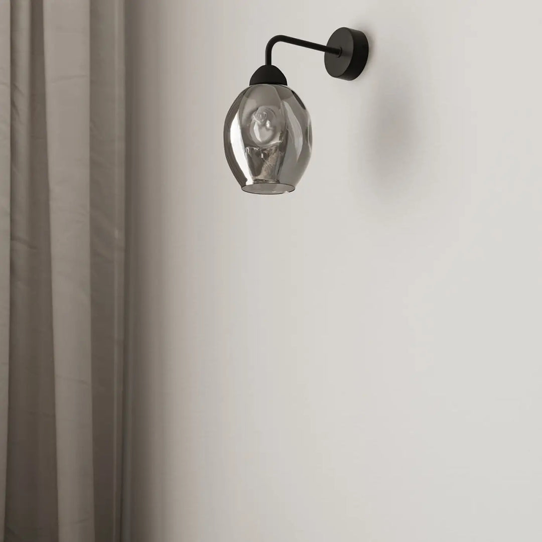 Une applique murale fillan 1 noir avec un abat-jour en verre fumé facetté, l’applique fillan au design élégant