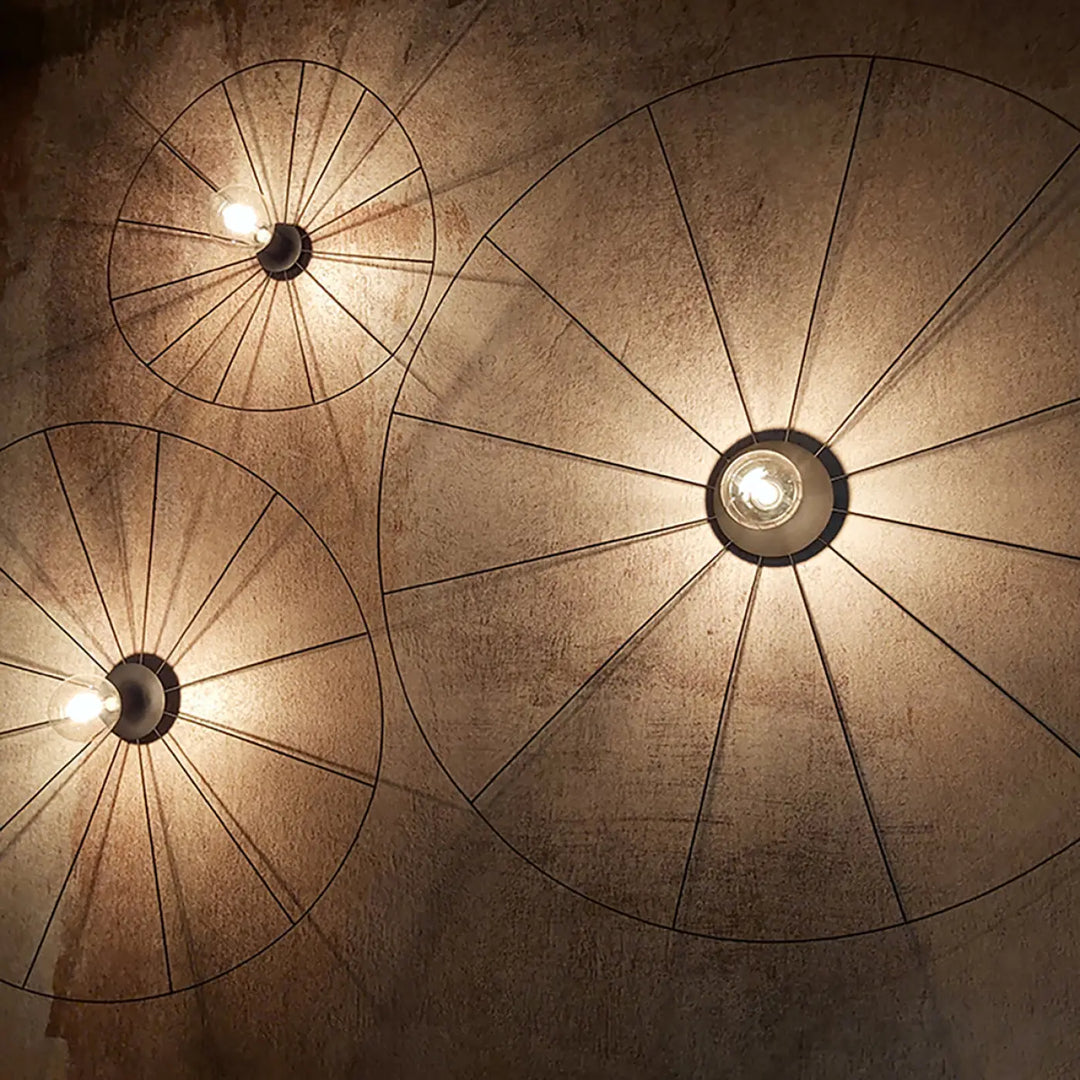 Trois lampes eskola circulaires en fil métallique noir au design unique stimulera de style industriel contre un mur texturé
