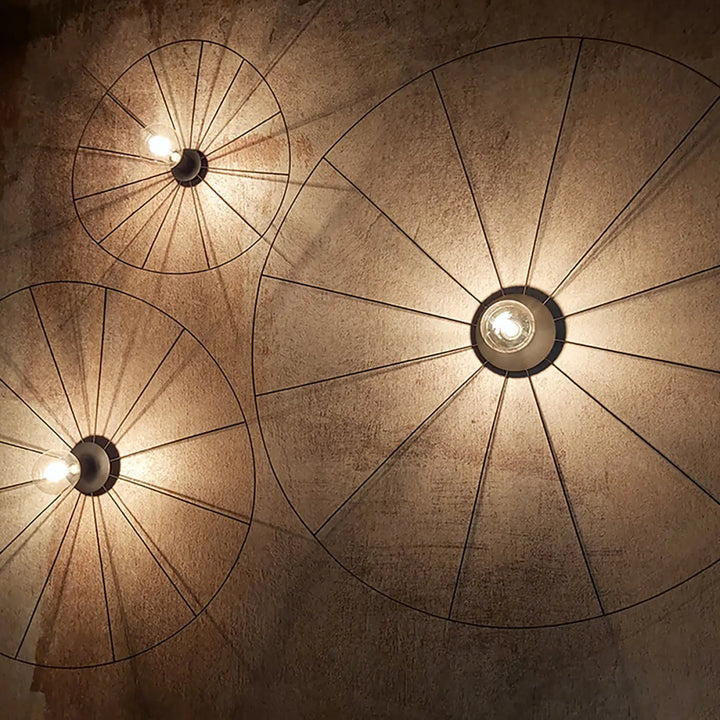 Trois lampes eskola circulaires en fil métallique noir au design unique stimulera de style industriel contre un mur texturé