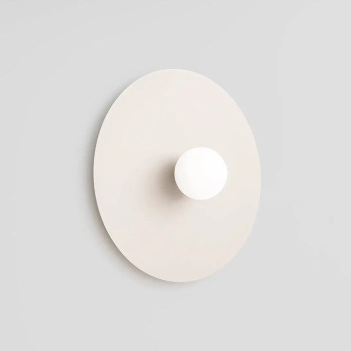 L’applique murale ake beige avec disque métallique rond et sphère laiteuse créent un éclairage minimaliste élégant
