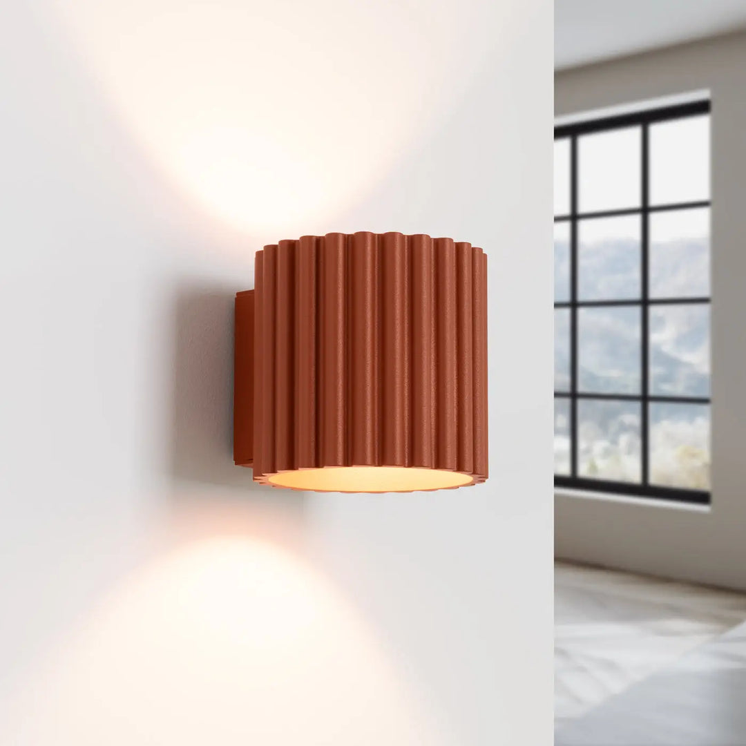 Applique murale aura rouge ochra avec forme unique inspirée et éclairage chaud diffus sur surface cannelée terracotta