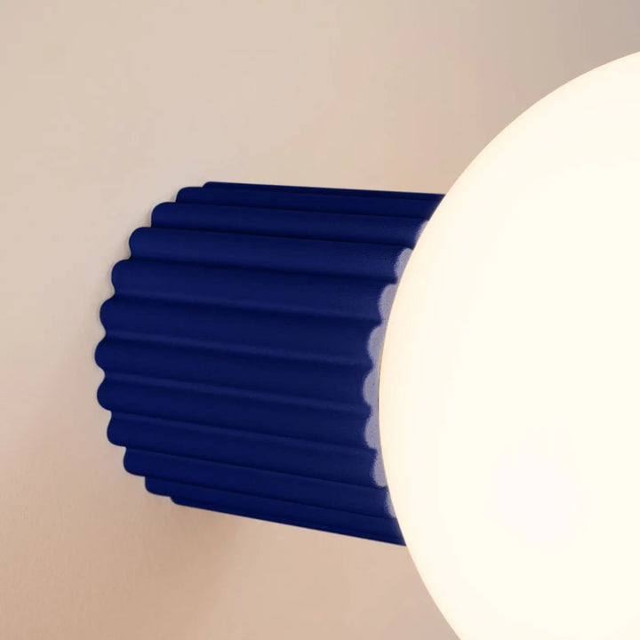 Applique murale halo ultramarine avec base cylindrique côtelée bleu profond et sphère laiteuse pour bureau décorative