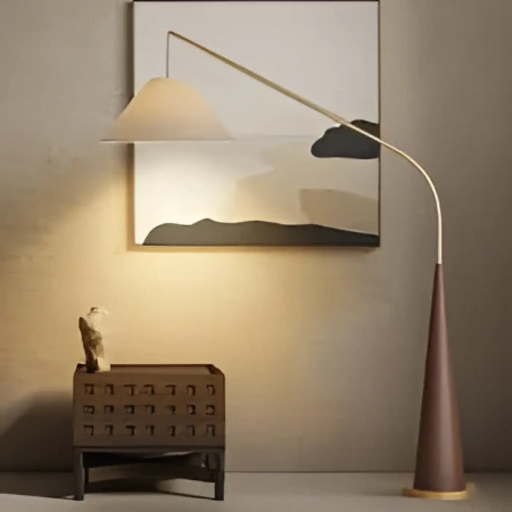 Lampadaire arvika avec pied métallique courbé argenté et base conique ton chaud pour salon ou chambre