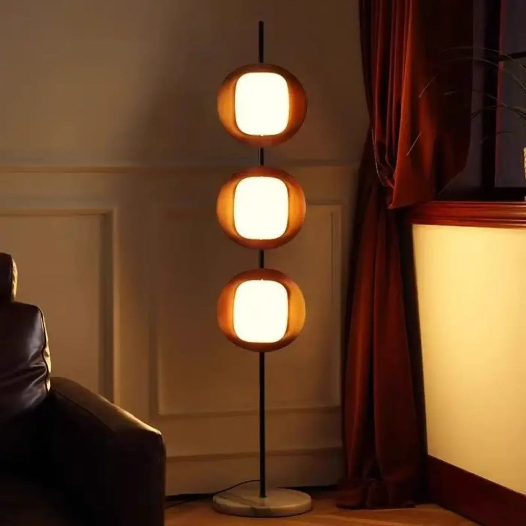 Lampadaire triom moderne avec trois abat-jours circulaires lumineux en bois chaud sur poteau en fer type noir et socle marbre