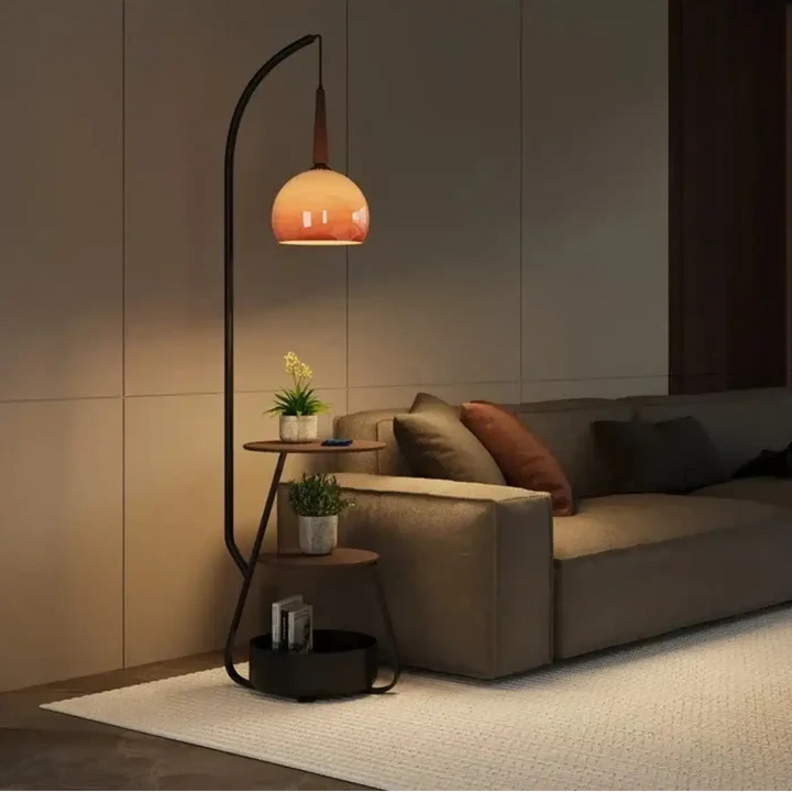 Lampadaire design curved en métal noir avec abat-jour en verre orange et étagères intégrées pour intérieur élégant