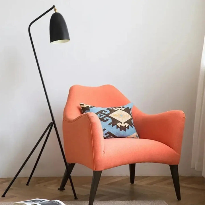 Orange armchair with geometric-patterned pillow highlighting lampadaire design minimaliste by trivio