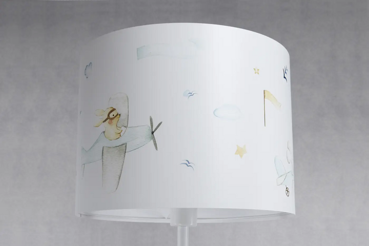 Lampadaire enfant blanc avec abat-jour cylindrique illustré d’un pilote lapin volant dans un décor aérien doux
