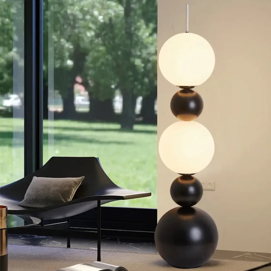 Lampadaire maitora avec boules lumineuses en verre blanc et finition mate sombre sur base noire pour décoration intérieure minimaliste chic