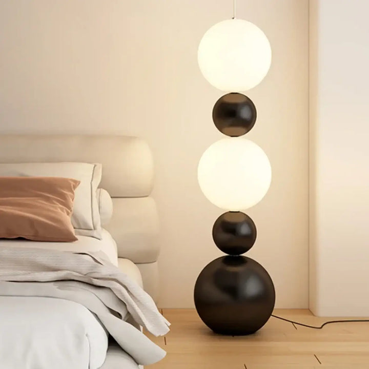Lampadaire maitora minimaliste chic avec quatre boules lumineuses empilées blanc brillant et noir mat pour décoration intérieure
